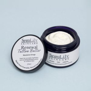 Renewal Tallow Butter, Mandarin Orange, open violet glass jar with its lid leaning against it
